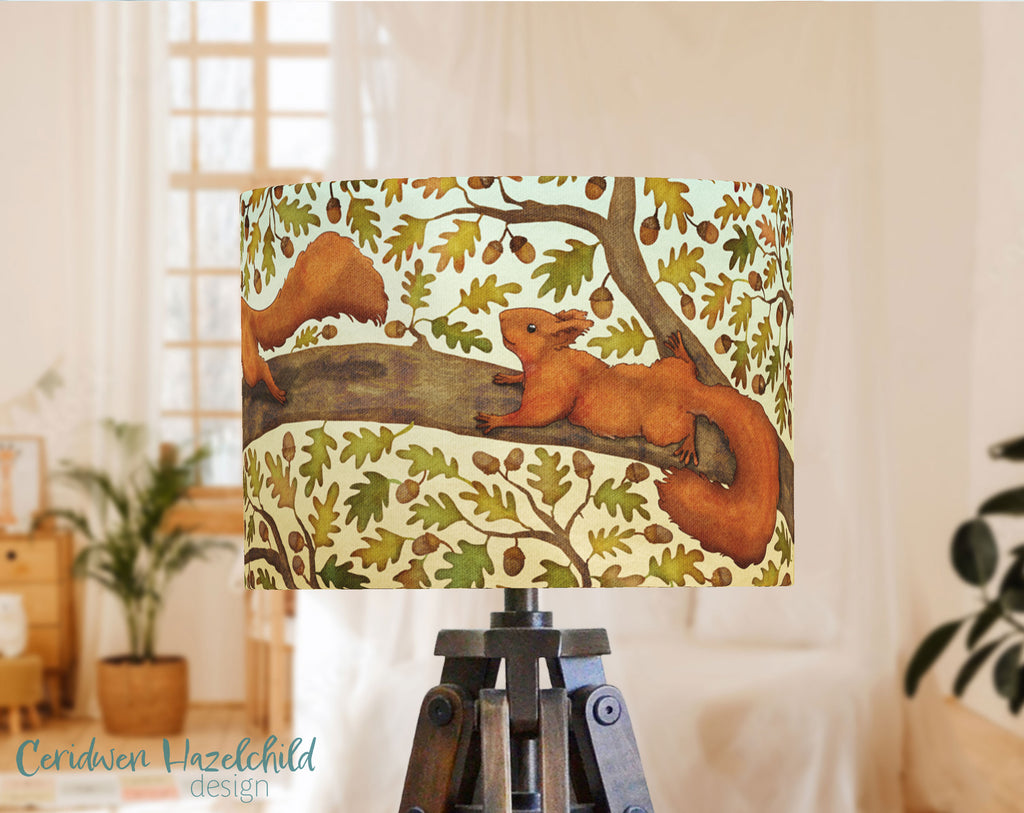 A handmade lampshade with an illustration of a red squirrel amongth oak leaves and acrorns, by Ceridwen Hazelchild.
