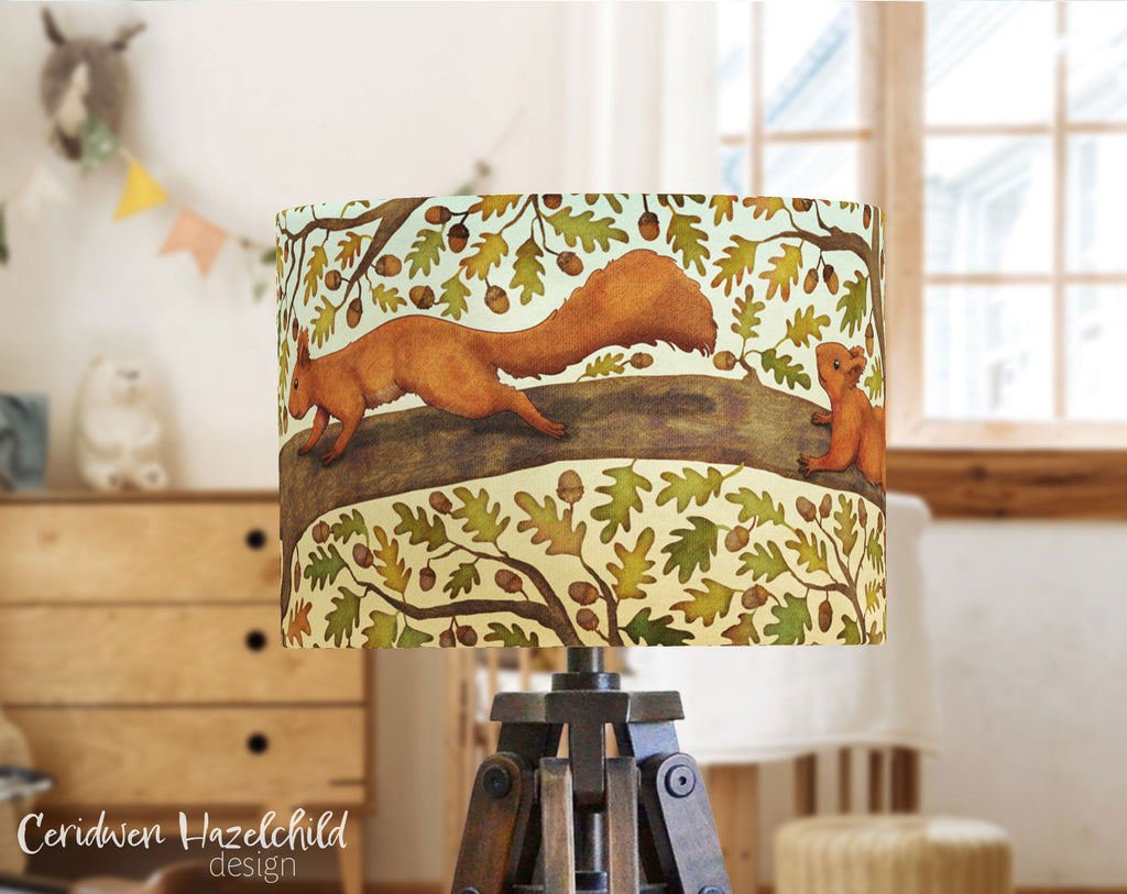 A lampshade in a child's bedroom, with an illustration of red squirrels in an oak tree, by Ceridwen Hazelchild 