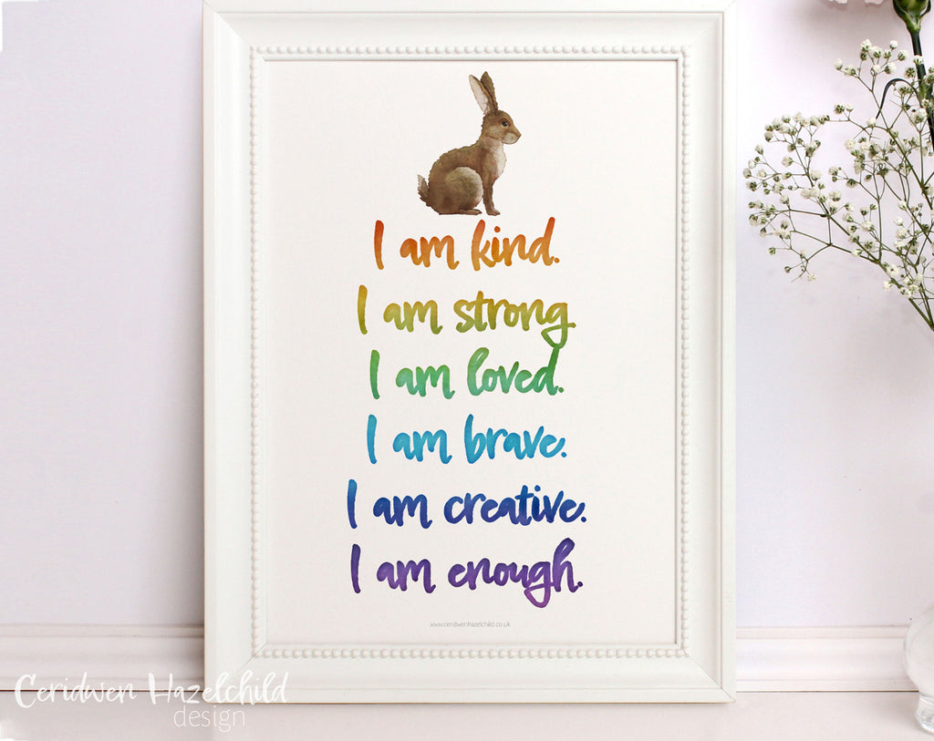 A framed poster featuring positive affirmations written in rainbow handwriting text and an illustration of a rabbit.