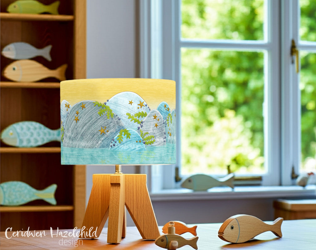 Rockpool-themed lampshade in a bright living room, styled beside a large window with wooden fish decorations.