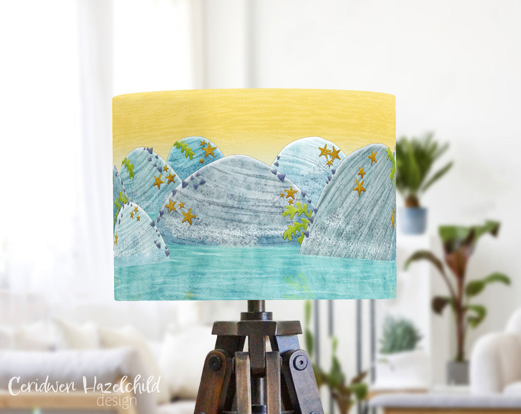 Rockpool lampshade by Ceridwen Hazelchild on a tripod lamp base in a bright, airy living room filled with natural light and leafy green plants.