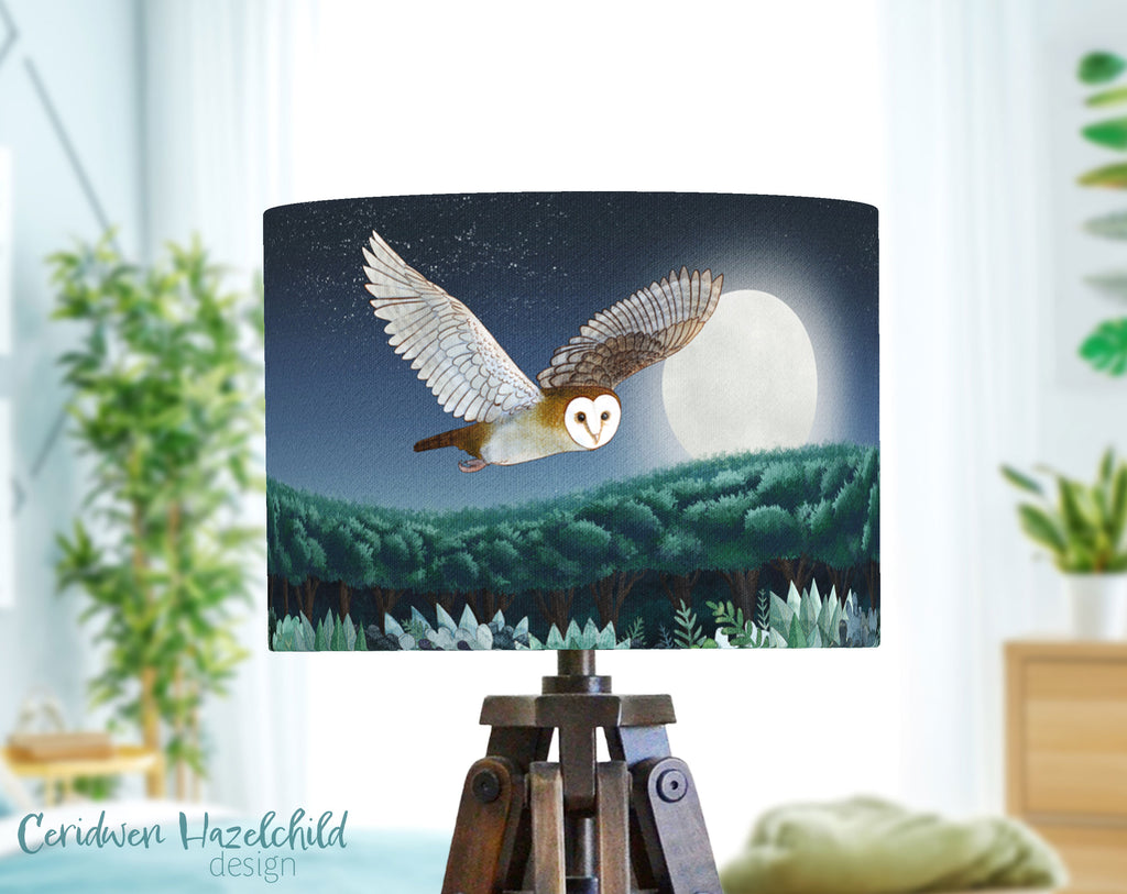 Lamp with an owl design against a night sky with a full moon by Ceridwen Hazelchild, in a bedroom with lots of plants.