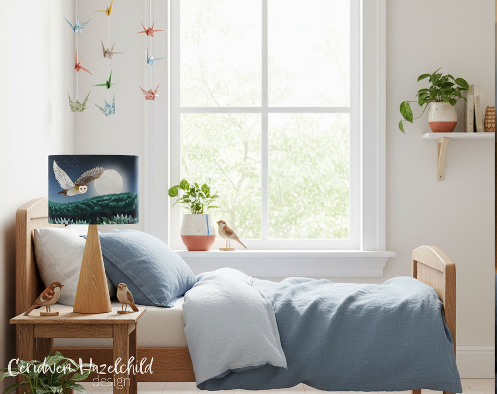 Children's bedroom with a bed, nightstand, and bedside lamp with an illustration of an owl flying over a nighttime woodland.