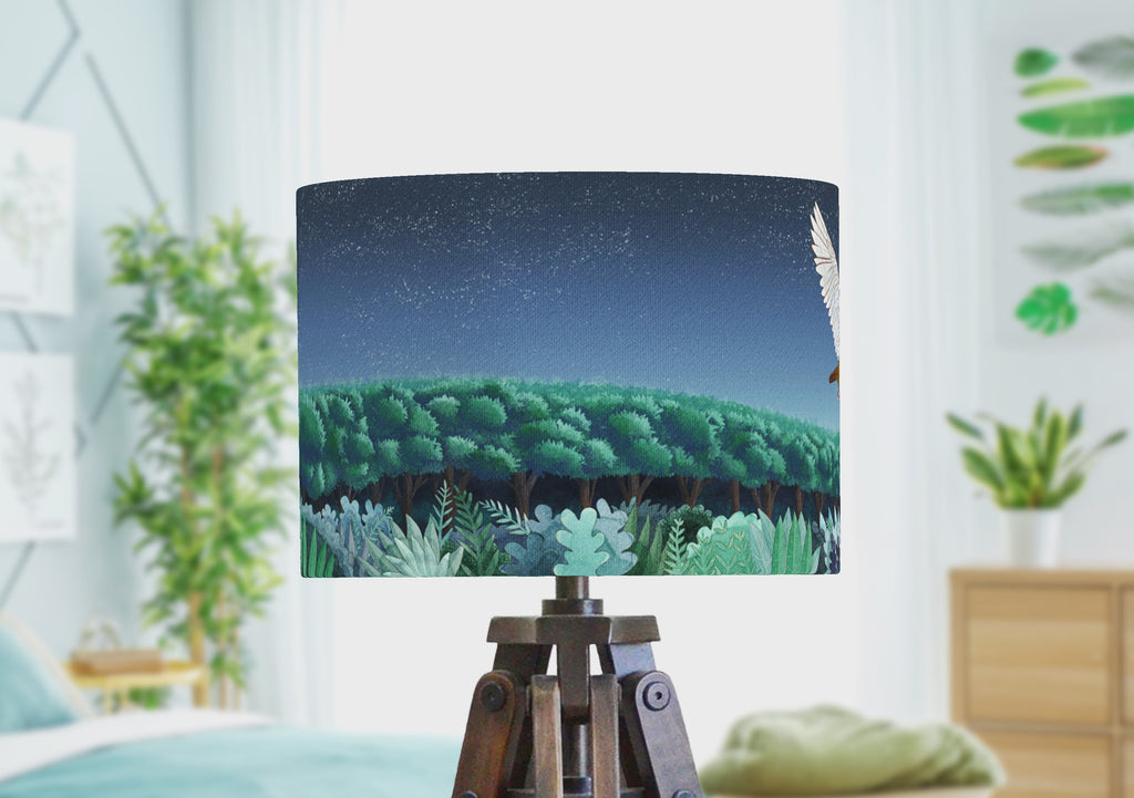 A woodland animal lampshade with desgin of a barn owl over a nighttime forest. The video shows the drum lampshade rotating to show the design wraps around.