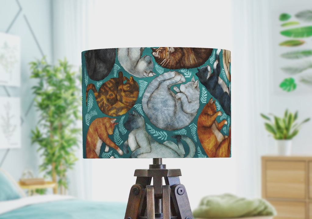 A handmade lampshade with sleeping cat illustrations, rotating to show the wrap-around design by the artist.
