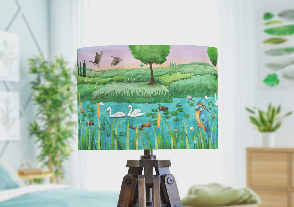 A handmade lampshade with wetland bird scene with herons, kingfishers, ducks, swans and geese. The drum lampshade rotated to show the full panoramic scene illustrated by the artist.