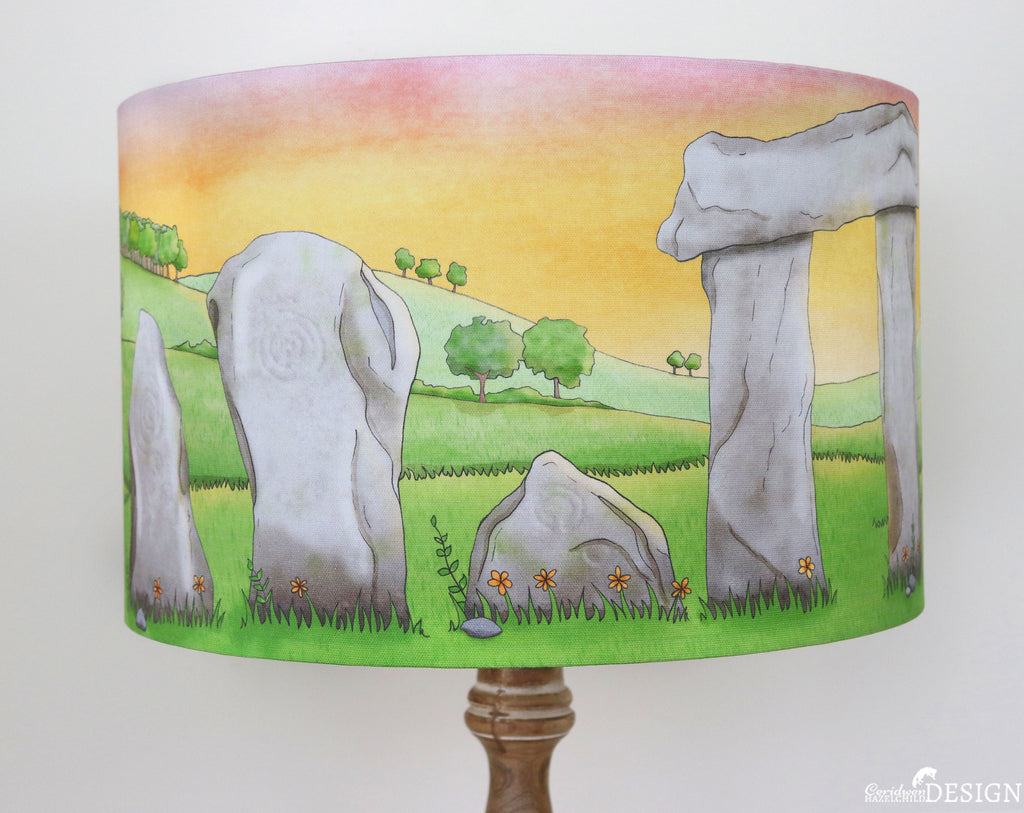 A lampshade with an illustration of Stonehenge against a sunrise by Ceridwen Hazelchild.